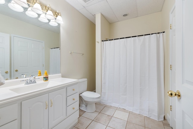 bathroom featuring tile patterned flooring, vanity, a paneled ceiling, and toilet