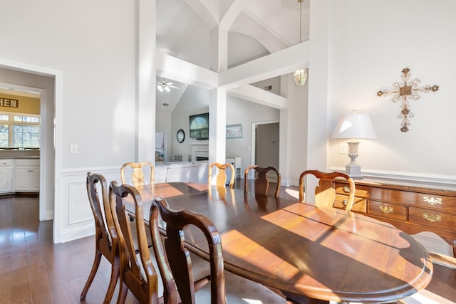 dining room featuring dark wood-type flooring, high vaulted ceiling, and ceiling fan