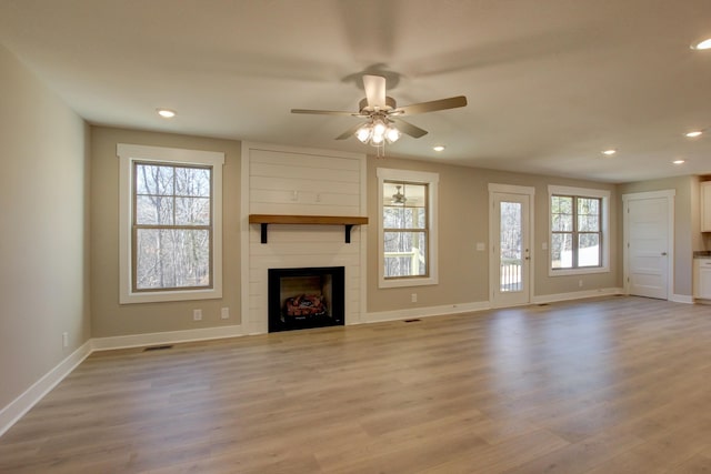 unfurnished living room with a large fireplace, a wealth of natural light, and light hardwood / wood-style flooring