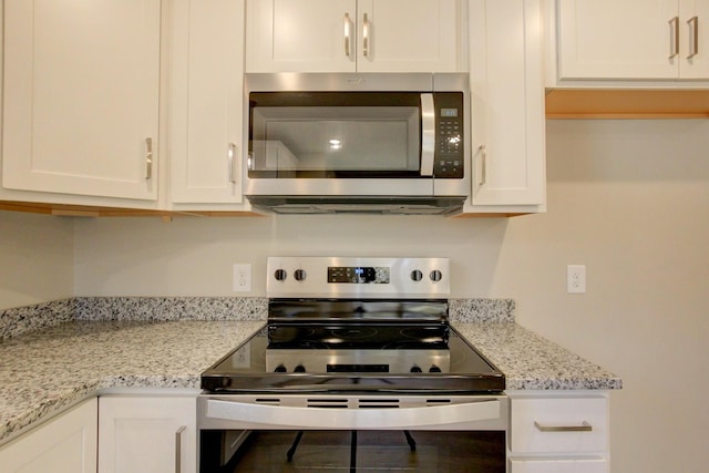 kitchen with white cabinetry, stainless steel appliances, and light stone countertops