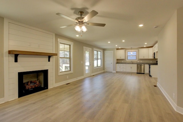 unfurnished living room with ceiling fan, sink, and light wood-type flooring