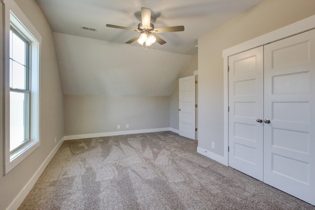 additional living space with vaulted ceiling, plenty of natural light, light colored carpet, and ceiling fan