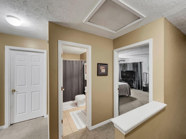 hallway with light colored carpet and a textured ceiling