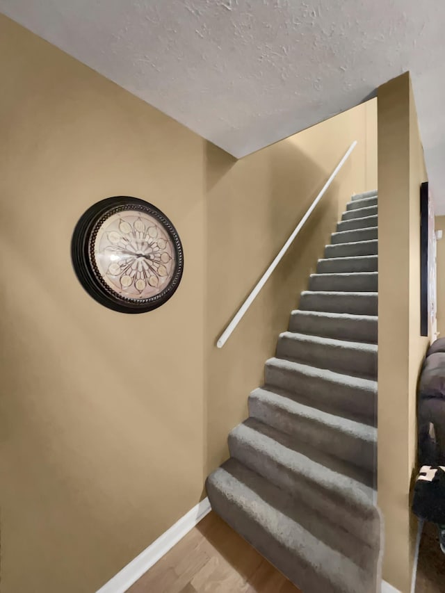 staircase with hardwood / wood-style floors and a textured ceiling