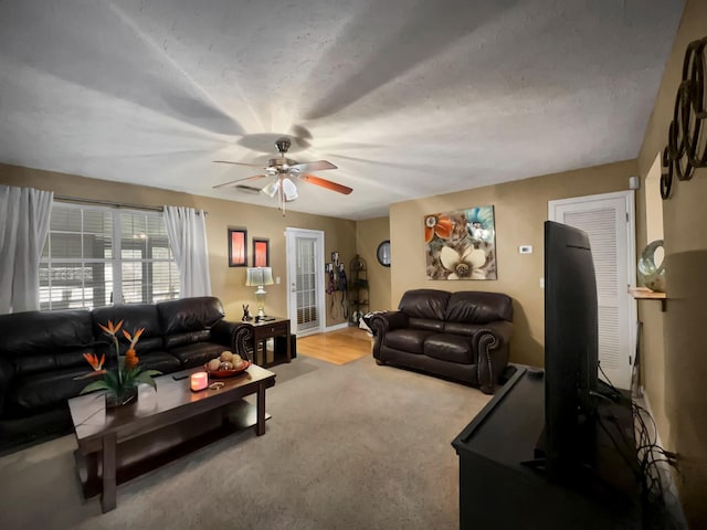 living room with a textured ceiling, light colored carpet, and ceiling fan