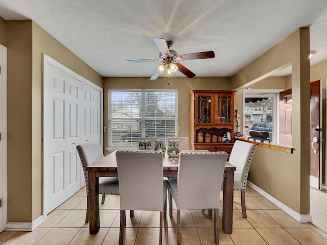 tiled dining room with ceiling fan and a textured ceiling