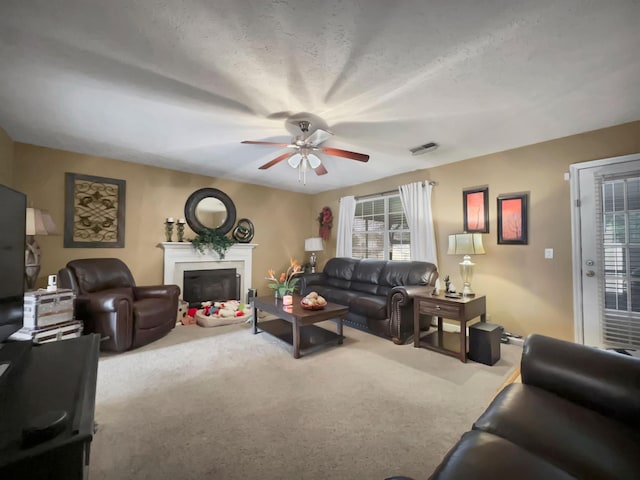 living room featuring ceiling fan, carpet floors, and a textured ceiling