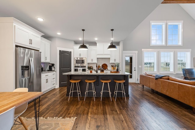 kitchen featuring light stone countertops, appliances with stainless steel finishes, a center island with sink, and white cabinets