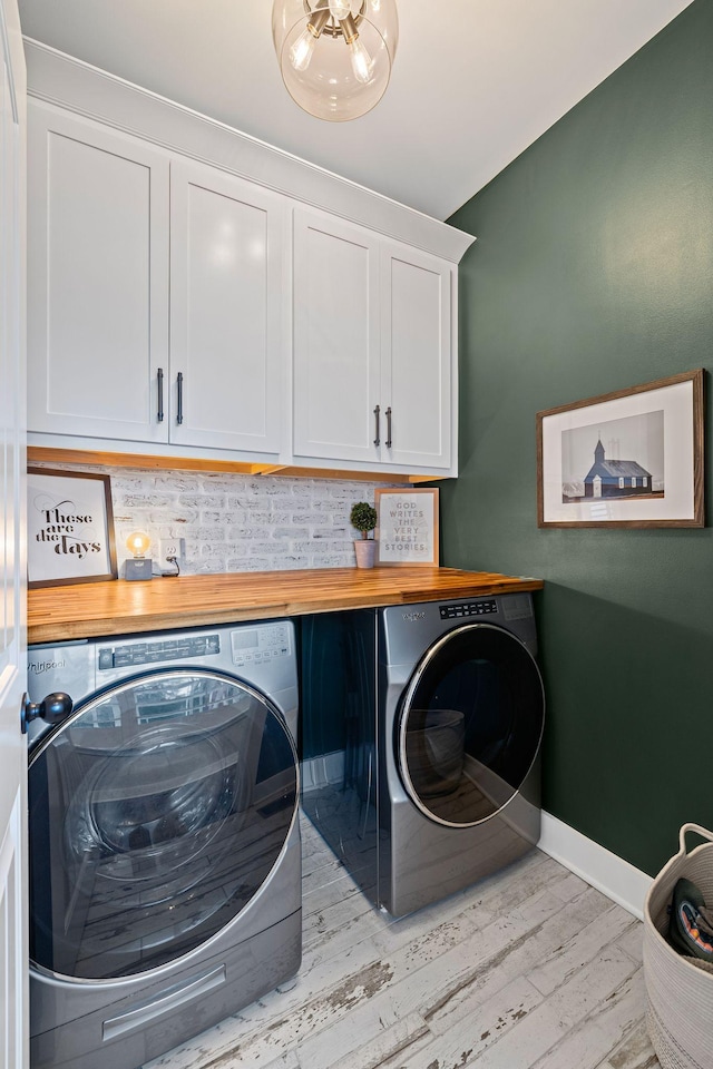 laundry area featuring cabinets, washer and dryer, and light hardwood / wood-style flooring