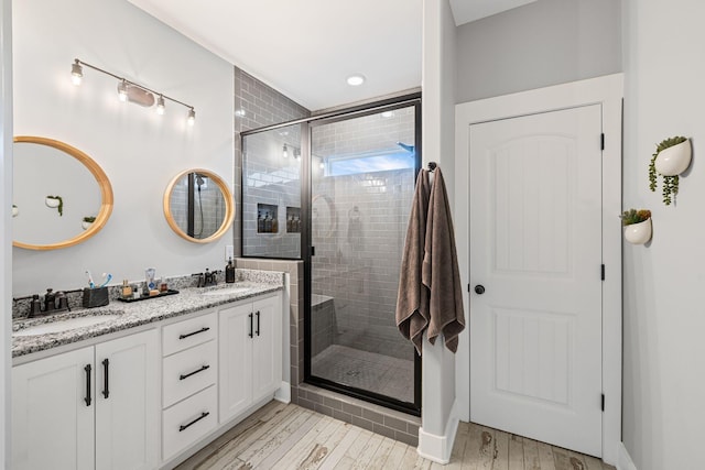 bathroom with a shower with door, vanity, and hardwood / wood-style flooring