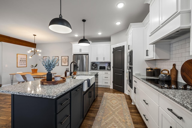 kitchen with stainless steel appliances, an island with sink, tasteful backsplash, and pendant lighting