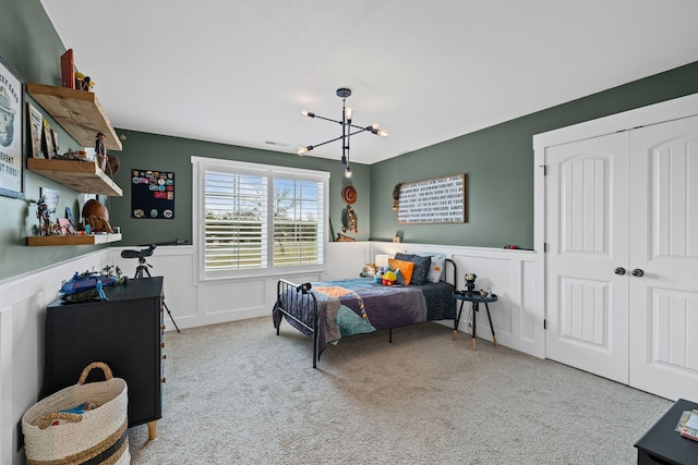 bedroom featuring light colored carpet, a notable chandelier, and a closet