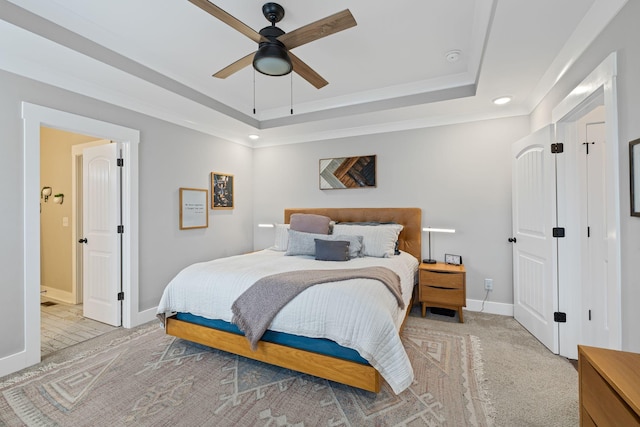 carpeted bedroom featuring a tray ceiling and ceiling fan