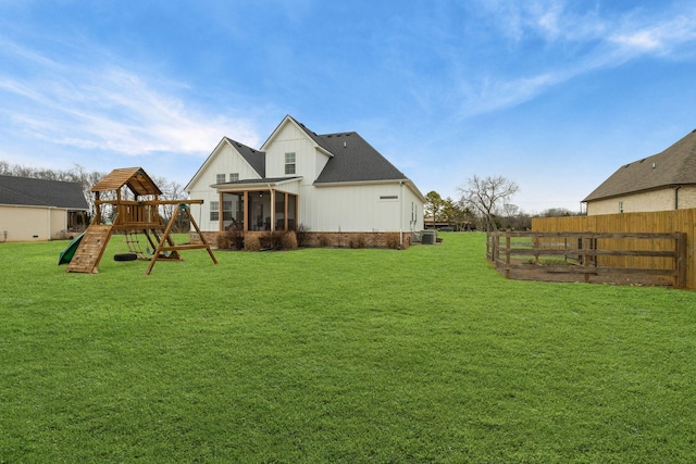 back of property featuring central AC unit, a sunroom, a playground, and a lawn