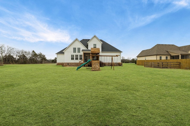 rear view of house with a playground and a yard