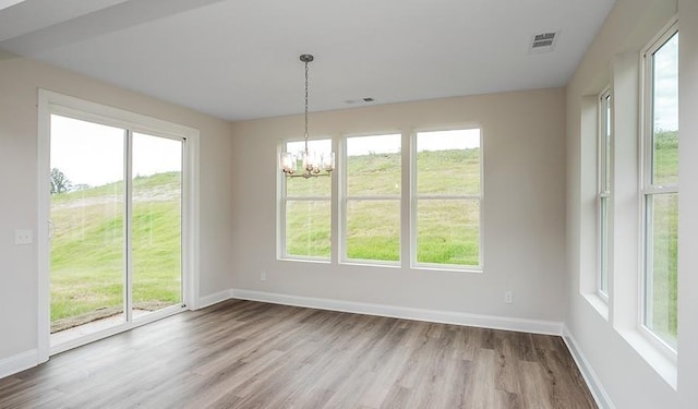 unfurnished dining area featuring a notable chandelier and light wood-type flooring