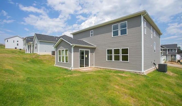 rear view of property featuring central AC unit and a lawn