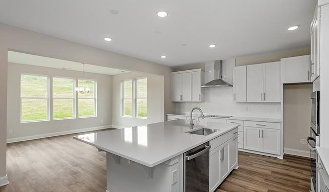 kitchen with dishwasher, white cabinetry, sink, wall chimney range hood, and a center island with sink