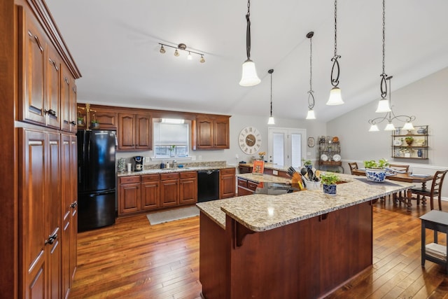 kitchen with decorative light fixtures, wood-type flooring, black appliances, and a spacious island