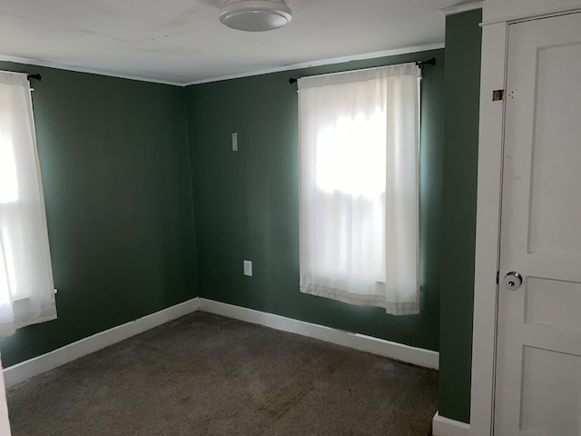 empty room featuring crown molding and dark carpet