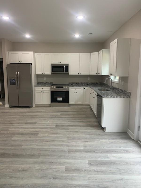 kitchen featuring white cabinetry, appliances with stainless steel finishes, sink, and light wood-type flooring