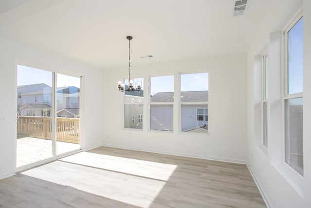 unfurnished dining area with hardwood / wood-style flooring and a notable chandelier