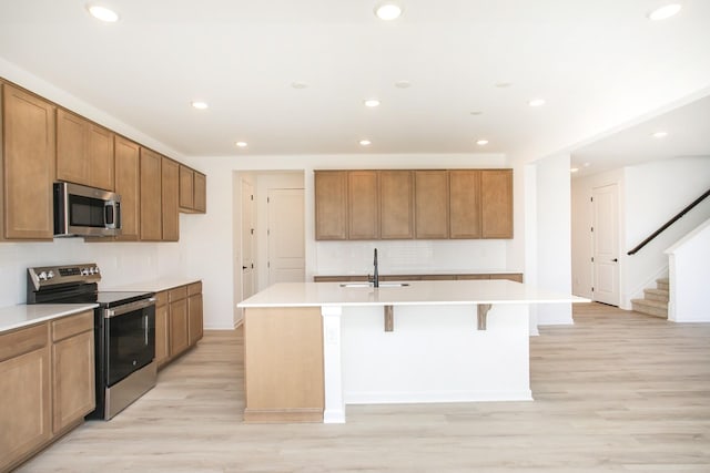 kitchen featuring stainless steel appliances, an island with sink, sink, and a breakfast bar