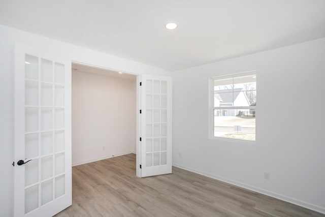 spare room featuring french doors and light hardwood / wood-style floors