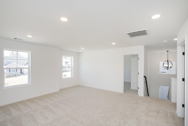 spare room featuring light carpet and a notable chandelier