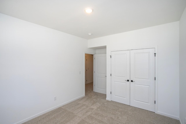 unfurnished bedroom with light colored carpet and a closet