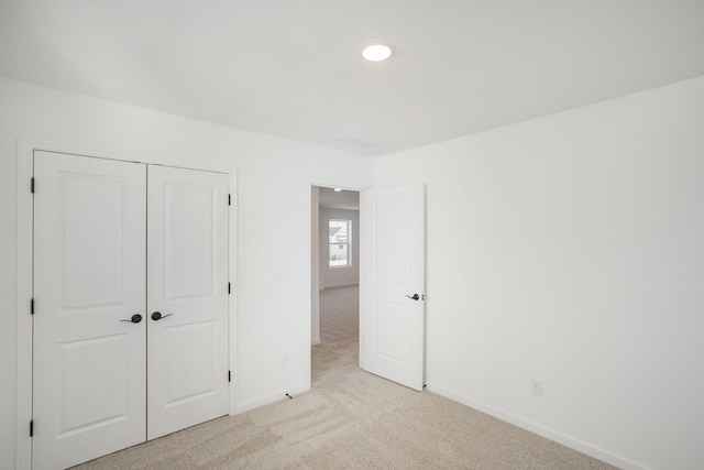 unfurnished bedroom with light colored carpet and a closet