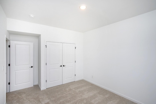 unfurnished bedroom featuring light colored carpet and a closet