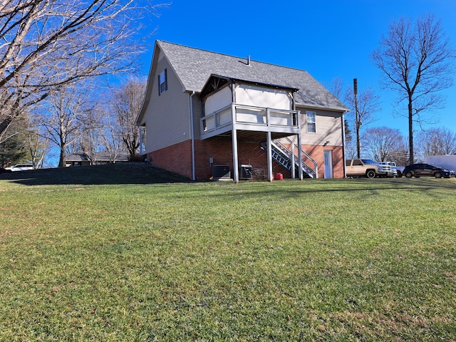 rear view of property with central AC and a lawn