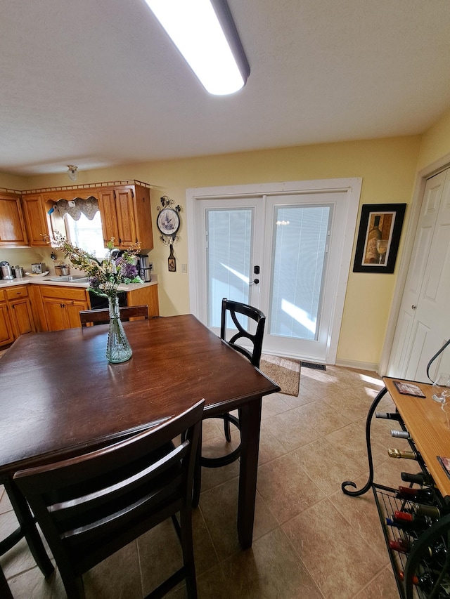 tiled dining room featuring sink and french doors