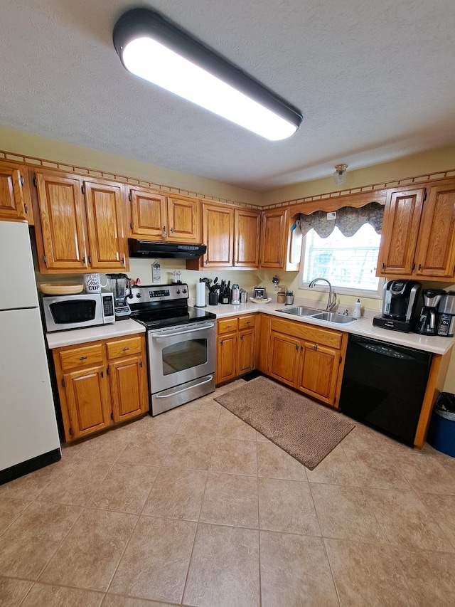 kitchen with light tile patterned flooring, stainless steel appliances, sink, and a textured ceiling