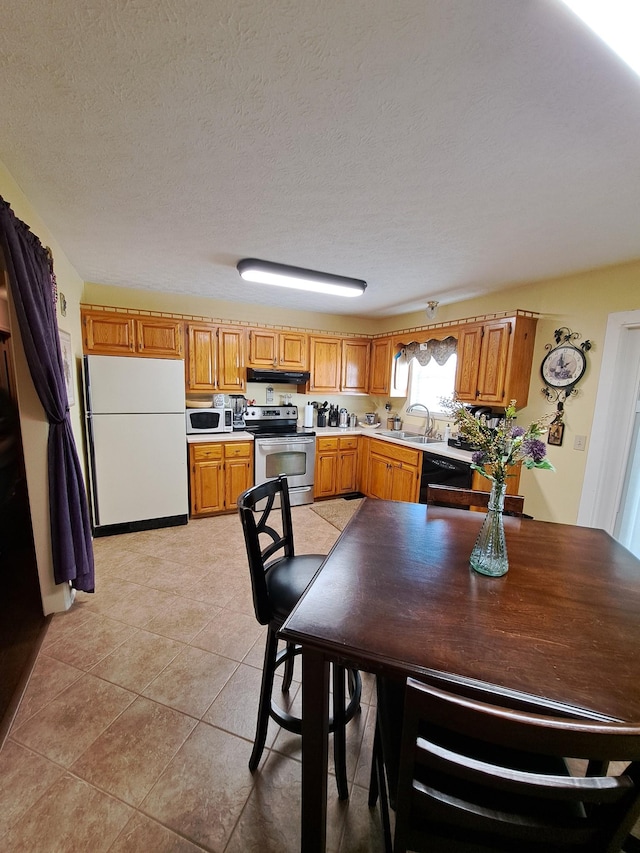 kitchen featuring sink, light tile patterned floors, a textured ceiling, and appliances with stainless steel finishes