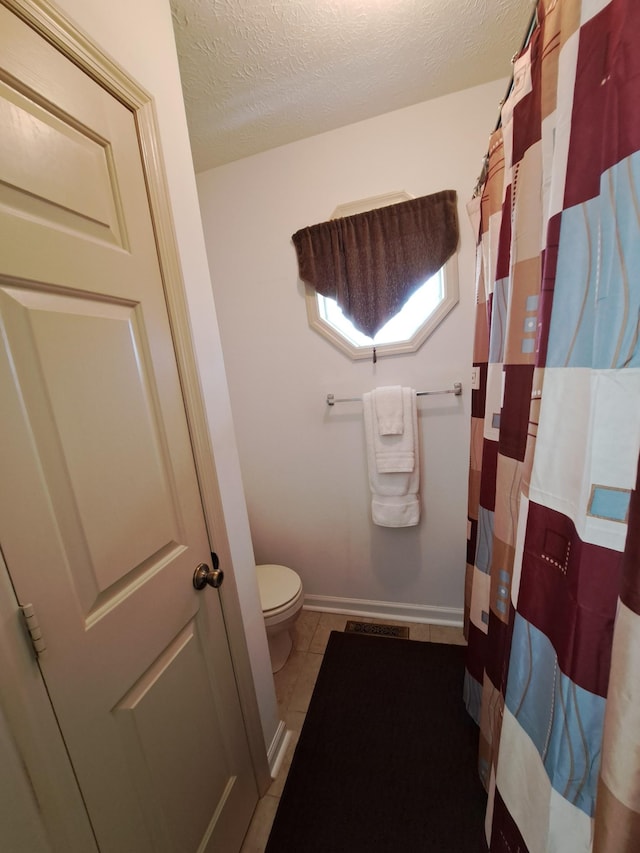 bathroom with tile patterned flooring, a textured ceiling, and toilet