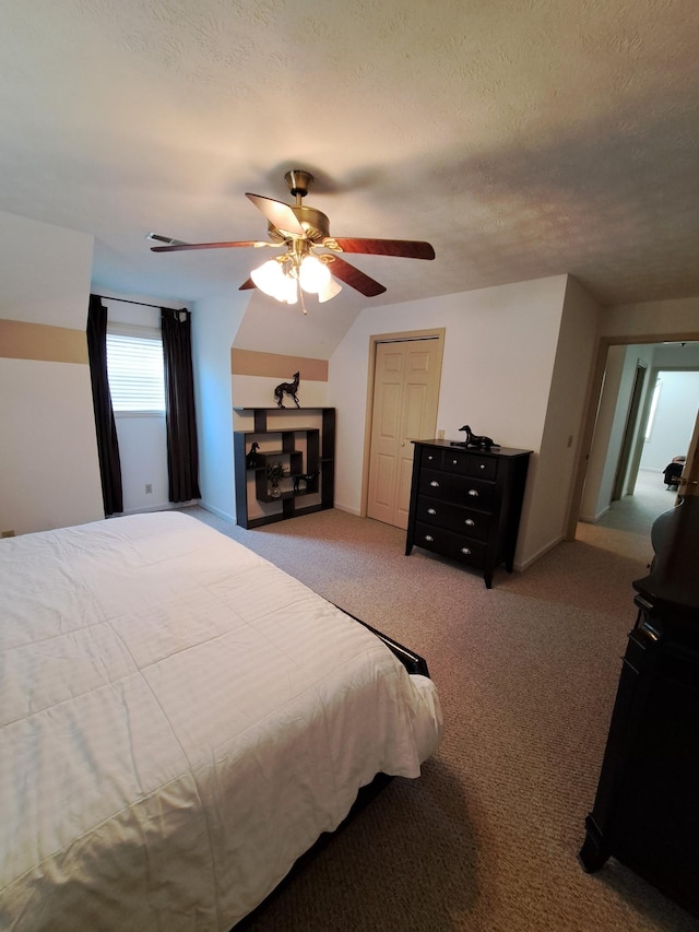 bedroom with ceiling fan, carpet flooring, and a textured ceiling