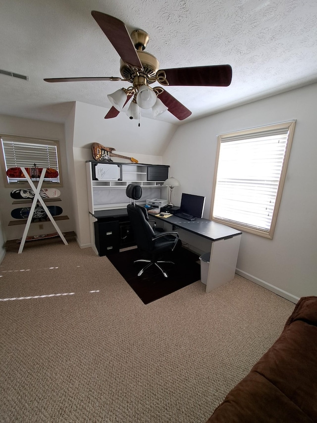 carpeted home office with ceiling fan, vaulted ceiling, and a textured ceiling