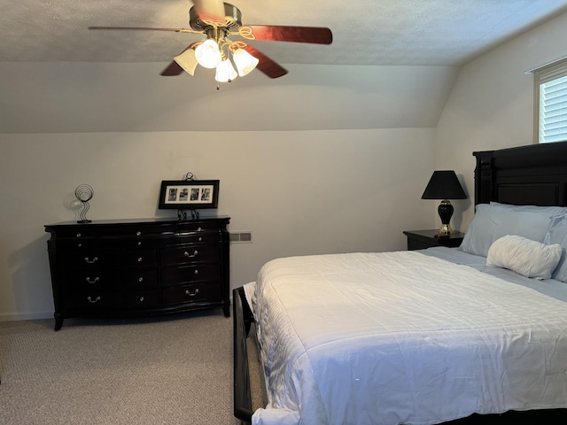 bedroom featuring a textured ceiling, vaulted ceiling, light colored carpet, and ceiling fan