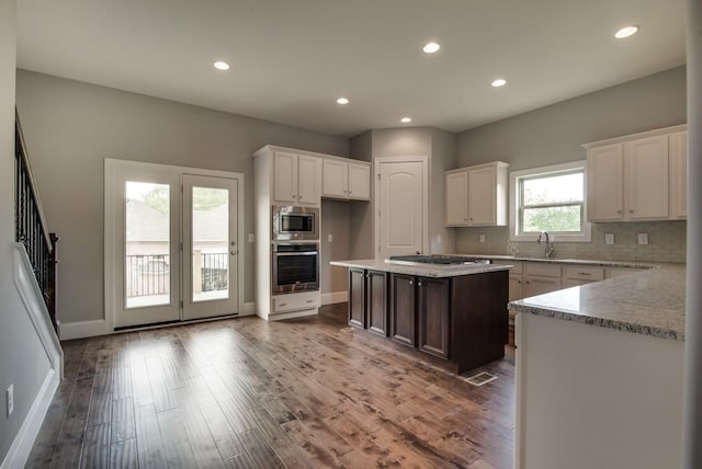 kitchen featuring stainless steel appliances, white cabinetry, a kitchen island, and wood-type flooring