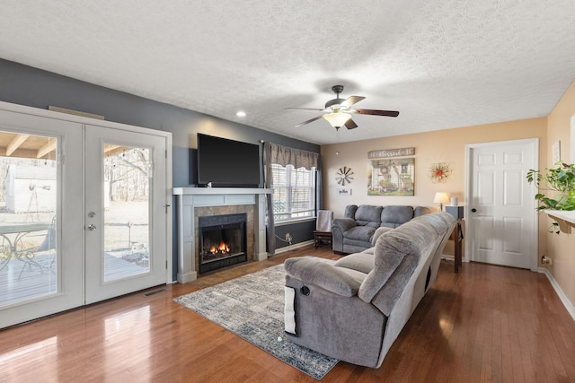 living room featuring french doors, dark hardwood / wood-style flooring, a tile fireplace, and a textured ceiling