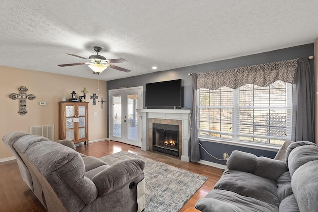 living room with hardwood / wood-style floors, a fireplace, ceiling fan, a textured ceiling, and french doors