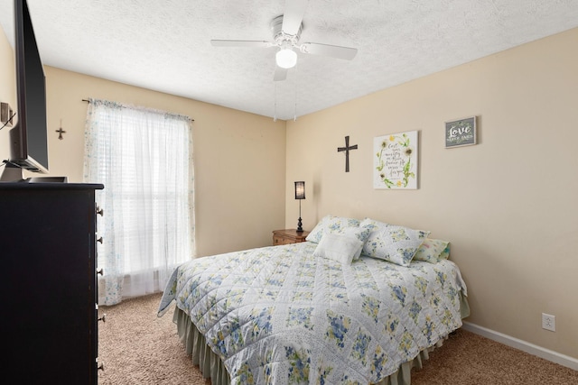 carpeted bedroom featuring ceiling fan and a textured ceiling