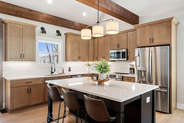 kitchen featuring a breakfast bar, sink, a center island, stainless steel appliances, and light wood-type flooring