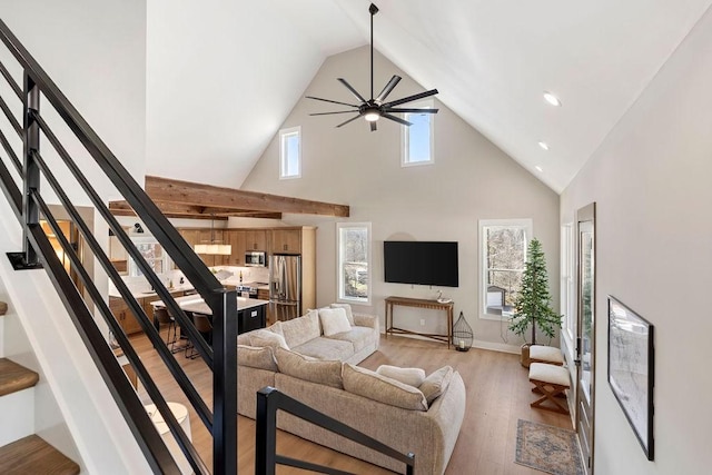 living room featuring ceiling fan, light hardwood / wood-style flooring, and a towering ceiling