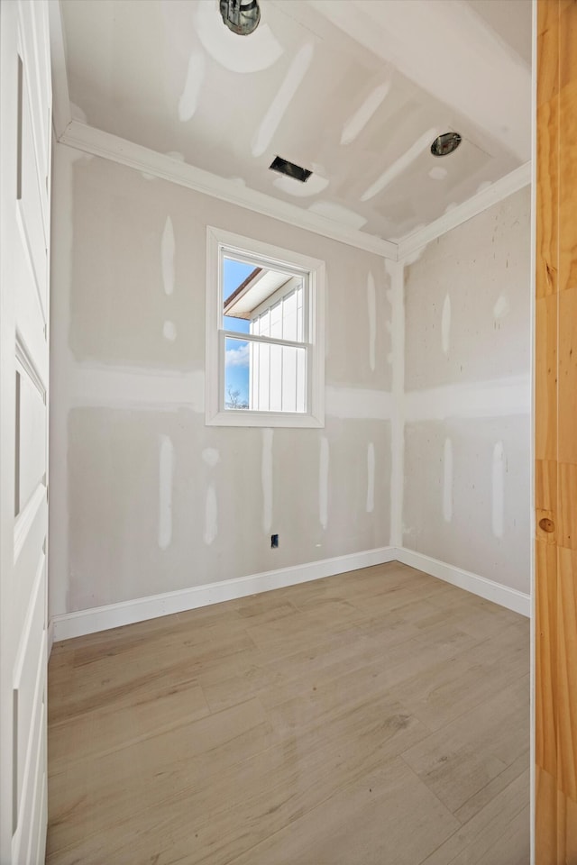 spare room with ornamental molding and light hardwood / wood-style flooring