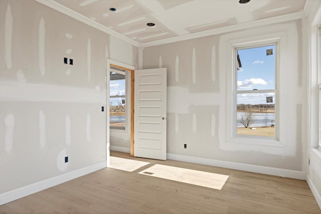 spare room featuring crown molding and light wood-type flooring