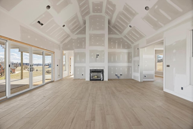 unfurnished living room featuring french doors, high vaulted ceiling, and light hardwood / wood-style floors