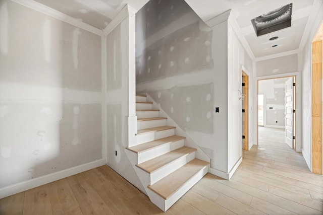 stairway with ornamental molding and wood-type flooring